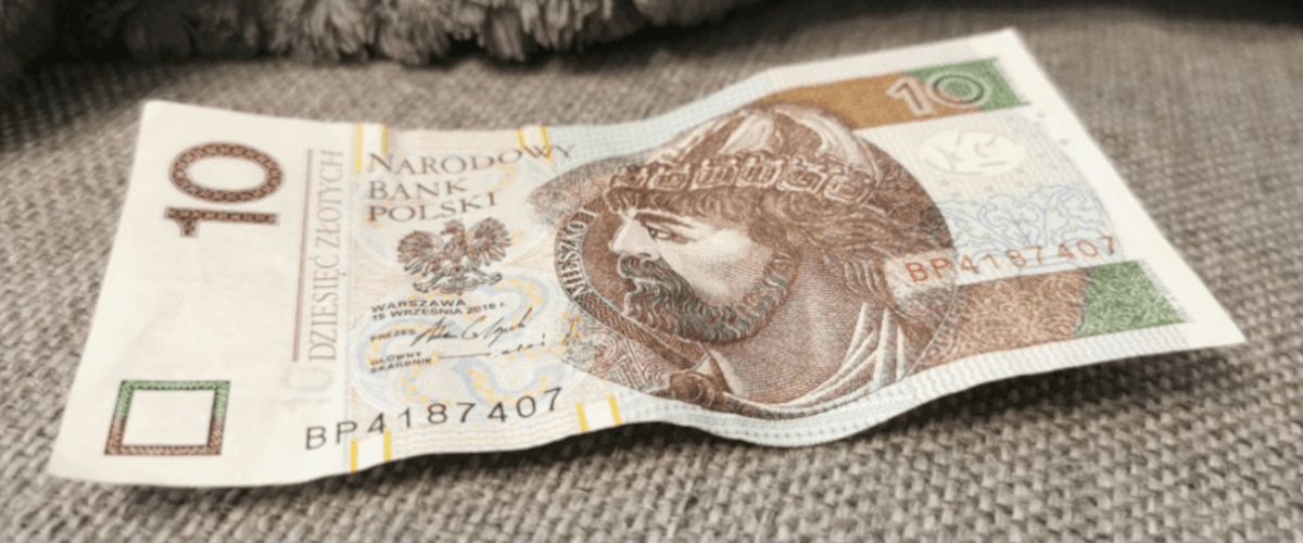 zdjęcie przedstawiające nieco wymięty banknot o nominale 10 zł leżący na szarym tapczanie