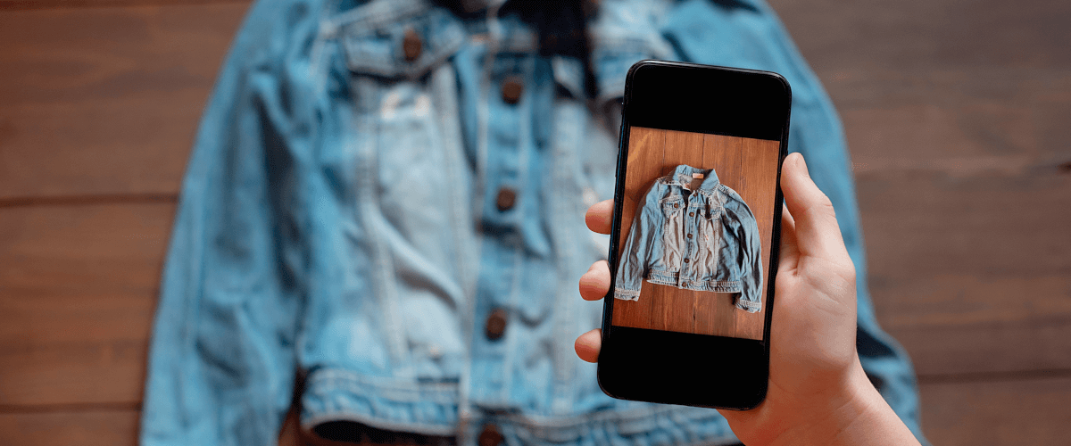 grafika przedstawiająca osobę robiącą zdjęcie smartfonem leżącej na podłodze kurtki dżinsowej