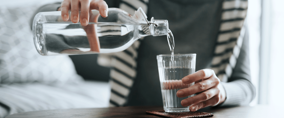 zdjęcie przedstawiające osobę nalewającą wodę z butelki do szklanki