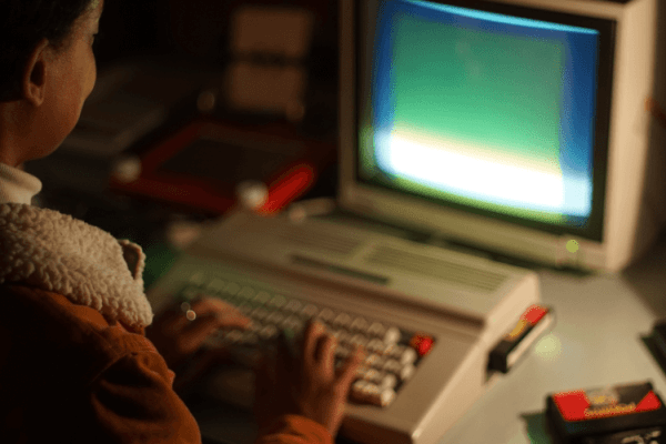 grafika przedstawiająca osobę pracującą na komputerze osobistym z lat 80. XX wieku