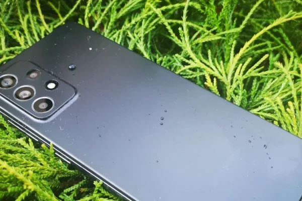 zdjęcie przedstawiające smartfona Samsung Galaxy A52s w czarnym/grafitowym kolorze leżącego ekranem do dołu na trawie