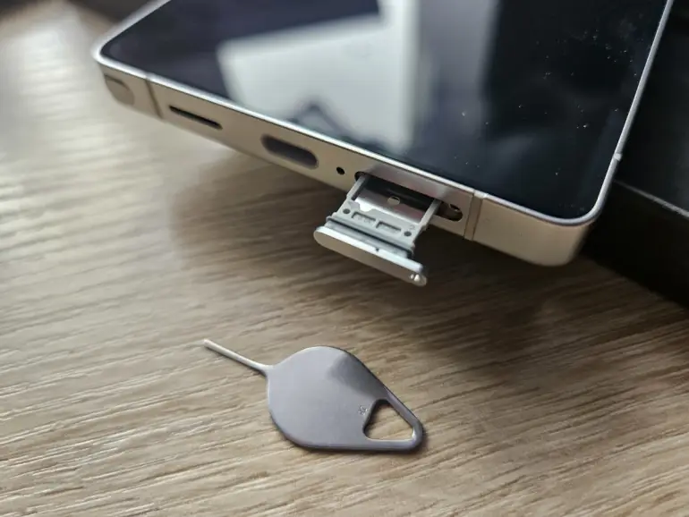 grafika przedstawiająca smartfona Samsung Galaxy S25 Ultra z wyciągniętą kartą SIM i igłą do tacki SIM