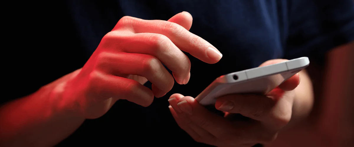 zdjęcie przedstawiające w przybliżeniu kobietę klikającą na ekran dotykowy smartfona